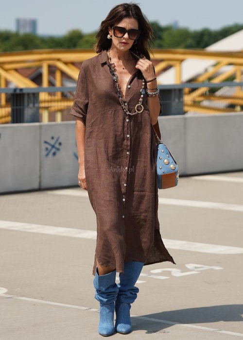 Brązowa lniana sukienka maxi w stylu szmizjerki, zapinana na guziki, o luźnym fasonie oversize, stylizowana z wysokimi kozakami i torebką.