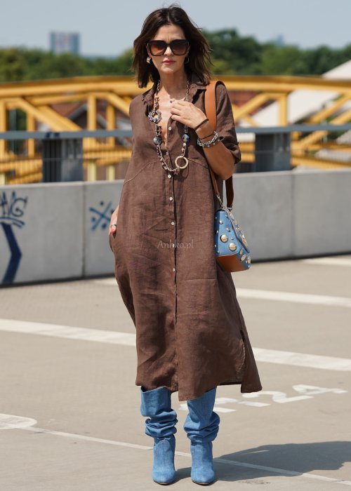 Brązowa lniana sukienka maxi w stylu szmizjerki, zapinana na guziki, o luźnym fasonie oversize, stylizowana z wysokimi kozakami i torebką.