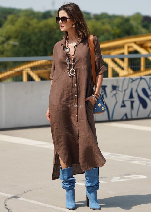 Brązowa lniana sukienka maxi w stylu szmizjerki, zapinana na guziki, o luźnym fasonie oversize, stylizowana z wysokimi kozakami i torebką.