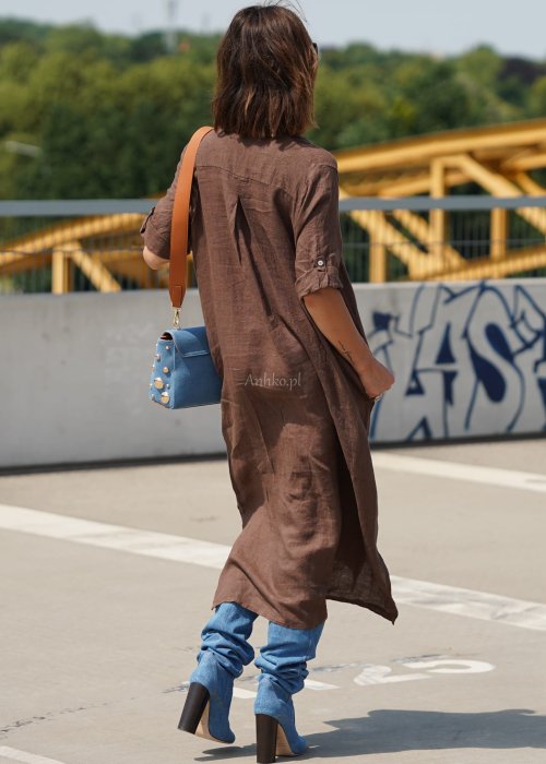Brązowa lniana sukienka maxi w stylu szmizjerki, zapinana na guziki, o luźnym fasonie oversize, stylizowana z wysokimi kozakami i torebką.