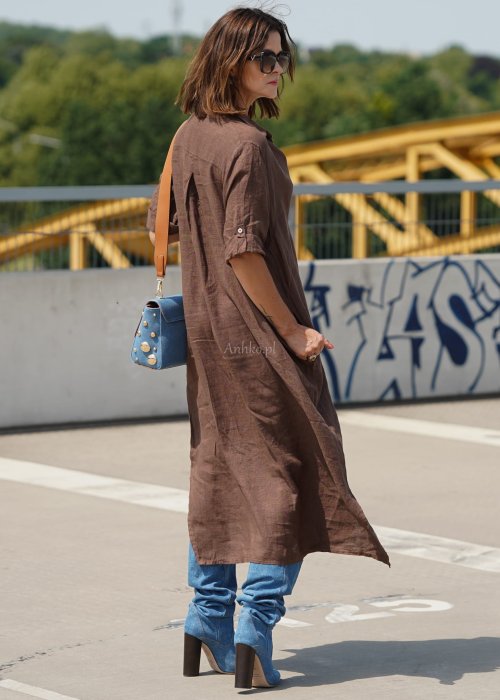 Brązowa lniana sukienka maxi w stylu szmizjerki, zapinana na guziki, o luźnym fasonie oversize, stylizowana z wysokimi kozakami i torebką.