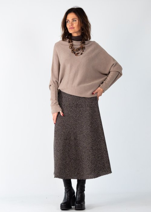 Sweter damski oversize w kolorze taupe o kroju nietoperzowym z dekoltem łódka i asymetrycznym dołem, stylizacja z biżuterią.