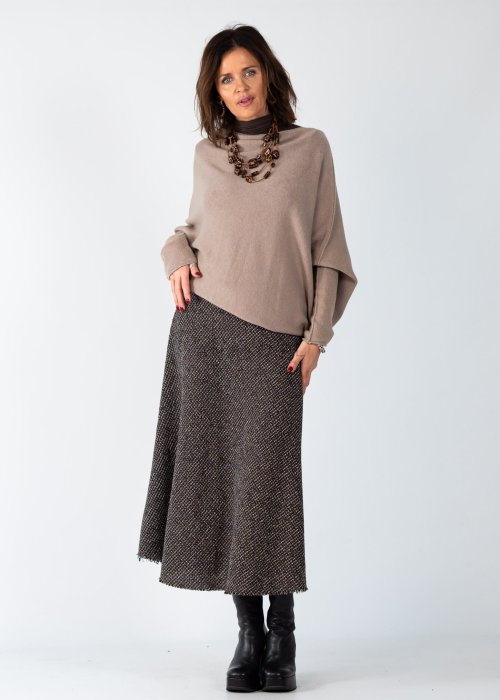 Sweter damski oversize w kolorze taupe o kroju nietoperzowym z dekoltem łódka i asymetrycznym dołem, stylizacja z biżuterią.