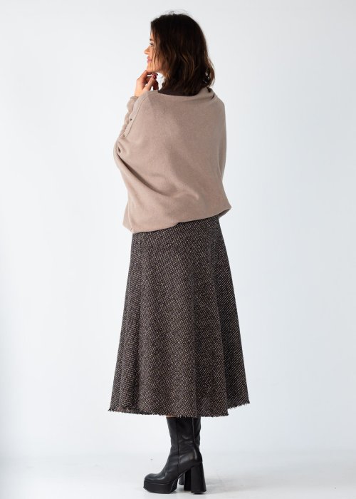 Sweter damski oversize w kolorze taupe o kroju nietoperzowym z dekoltem łódka i asymetrycznym dołem, stylizacja z biżuterią.