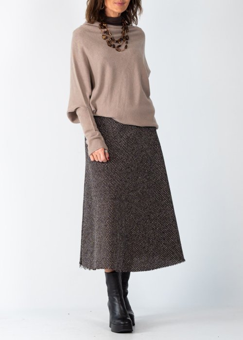Sweter damski oversize w kolorze taupe o kroju nietoperzowym z dekoltem łódka i asymetrycznym dołem, stylizacja z biżuterią.