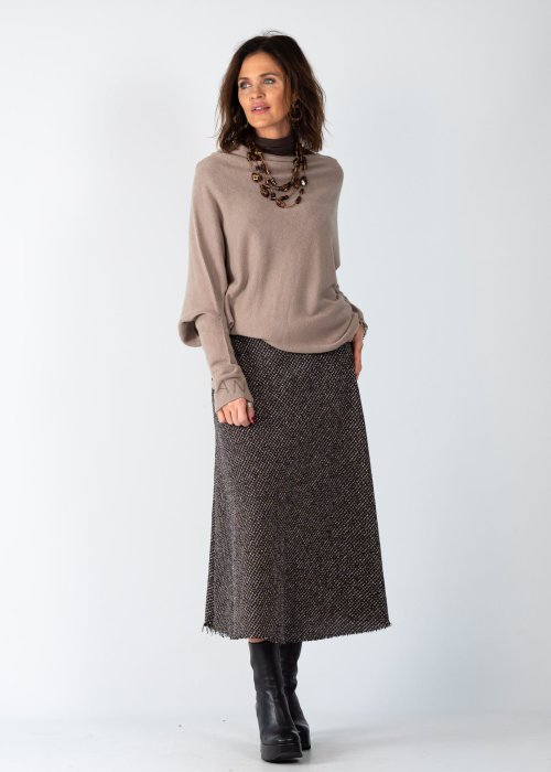 Sweter damski oversize w kolorze taupe o kroju nietoperzowym z dekoltem łódka i asymetrycznym dołem, stylizacja z biżuterią.