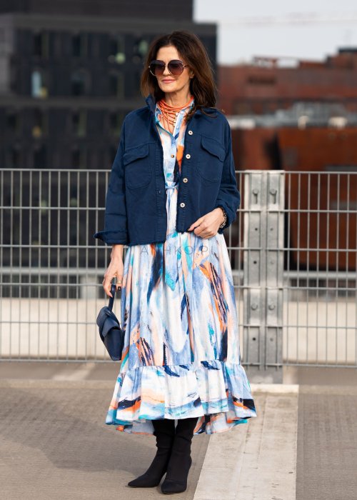 Sukienka maxi w artystyczny print w odcieniach błękitu, pomarańczu i granatu z efektownym wiązaniem w talii. Zwiewny fason z falbaną przy dole oraz koszulową górą nadaje sylwetce lekkości i elegancji.