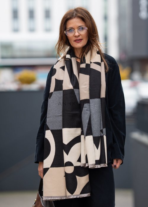 Stylizacja jesienna: beżowa czapka beanie z naszywką uśmiechu oraz duży szalik w beżowo-czarny wzór graficzny, połączone z szarą bluzą oversize i jeansami