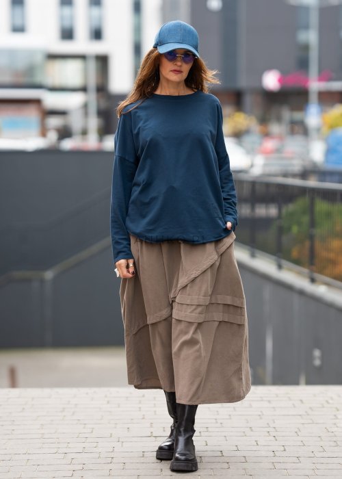 Ciemnoniebieska bluza damska oversize z długim rękawem i naszywką na froncie. Luźny fason w miejskiej stylizacji z czapką i spódnicą.