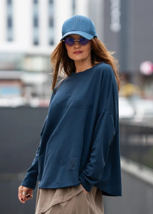 Ciemnoniebieska bluza damska oversize z długim rękawem i naszywką na froncie. Luźny fason w miejskiej stylizacji z czapką i spódnicą.