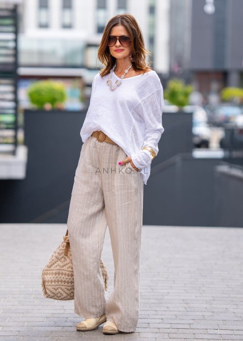 Biała bluzka lniana o luźnym kroju, z długim rękawem i naturalną strukturą materiału, stylizacja miejska z lnianymi spodniami.