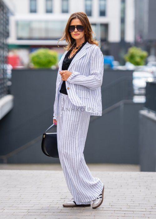 Spodnie lniane damskie w białym kolorze w pionowe paski z szerokimi nogawkami i elastycznym pasem. Stylizacja lekka i elegancka.