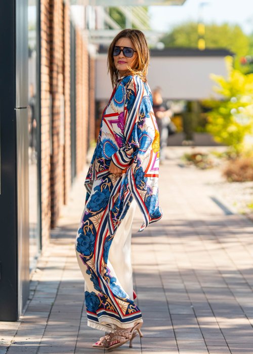 Jasne spodnie damskie z szeroką nogawką, zdobione kolorowym kwiatowym nadrukiem w stylu boho