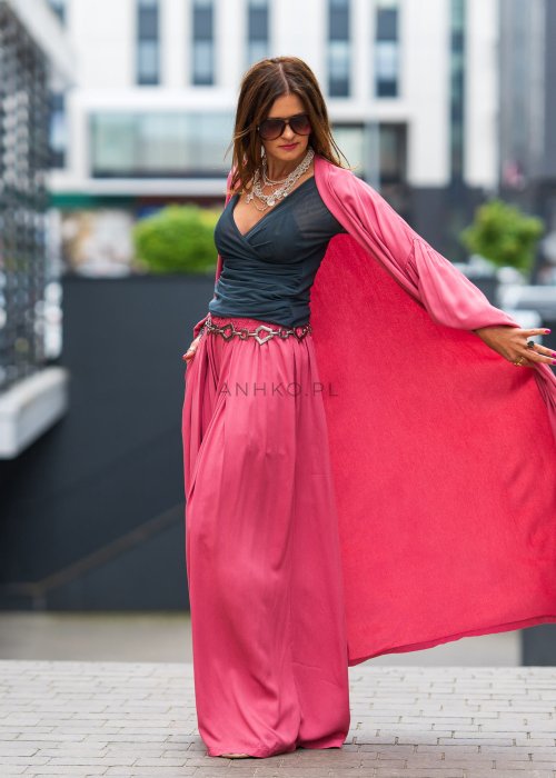 Różowe kimono damskie maxi z długim, płynnie układającym się fasonem i bufiastymi rękawami. Model pokazany w stylizacji z topem i szerokimi spodniami, w nowoczesnym miejskim wydaniu.