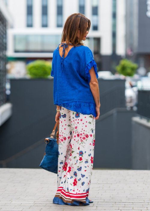 Chabrowa lniana bluzka damska z dodatkiem jedwabiu, falbaniastymi rękawami i asymetrycznym wykończeniem z ozdobnym wiązaniem. Stylowy model do codziennych i eleganckich stylizacji.