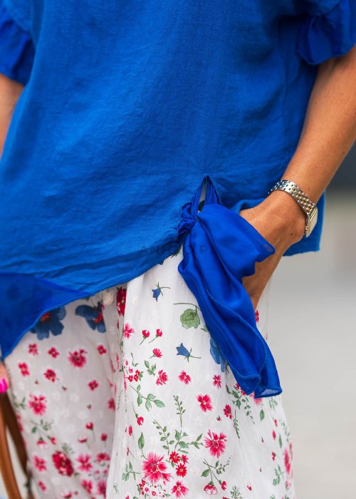 Chabrowa lniana bluzka damska z dodatkiem jedwabiu, falbaniastymi rękawami i asymetrycznym wykończeniem z ozdobnym wiązaniem. Stylowy model do codziennych i eleganckich stylizacji.