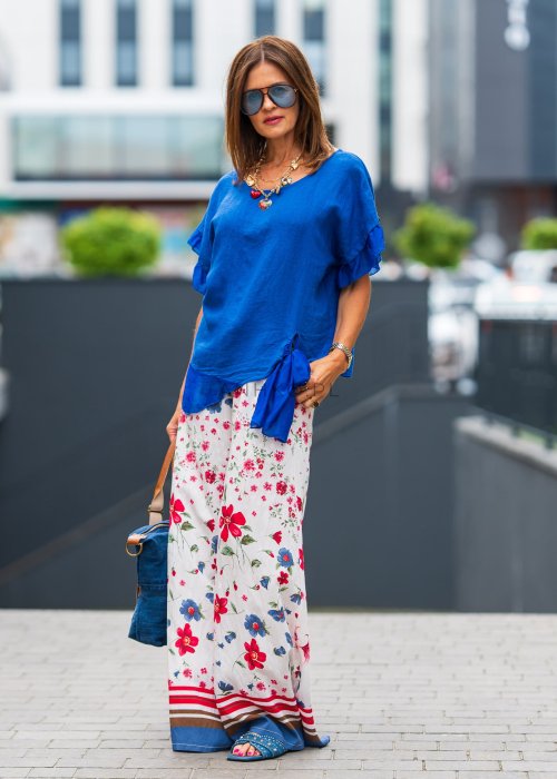 Chabrowa lniana bluzka damska z dodatkiem jedwabiu, falbaniastymi rękawami i asymetrycznym wykończeniem z ozdobnym wiązaniem. Stylowy model do codziennych i eleganckich stylizacji.