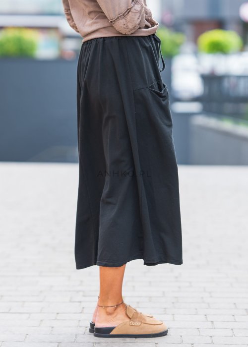Czarna spódnica midi z dużymi drewnianymi guzikami z przodu, elastyczną talią na troczek i praktycznymi kieszeniami po bokach, w stylu casual.