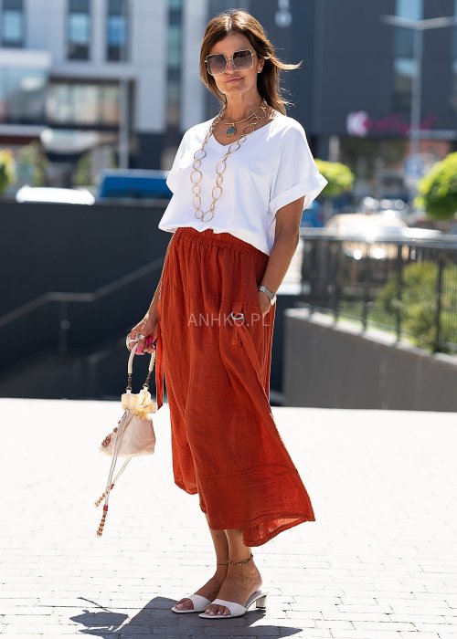 Spódnica Lniana Nomad CeglanaLniana, ruda spódnica midi o luźnym kroju z kieszeniami i ozdobnymi paskami, w stylu boho idealna na letnie stylizacje