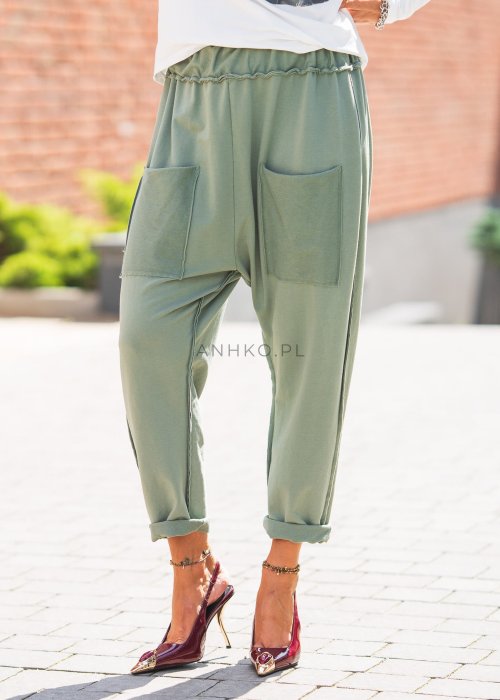 Zielone spodnie damskie oversize z dużymi kieszeniami i elastycznym pasem. Stylizacja z jasną bluzką i eleganckimi szpilkami w miejskim stylu.