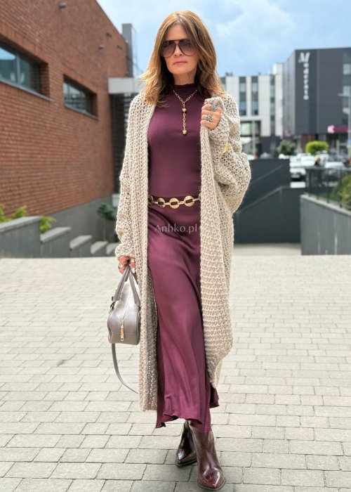 Długi oversize kardigan damski z grubego beżowego splotu, z obniżoną linią ramion, w stylu boho i casualowej mody damskiej