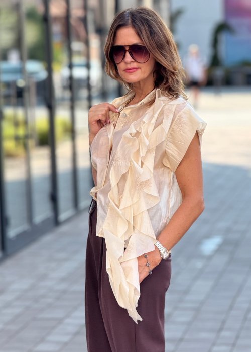 Beżowa bluzka damska bez rękawów, zapinana na guziki, z dekoracyjną falbaną z przodu, elegancki styl boho