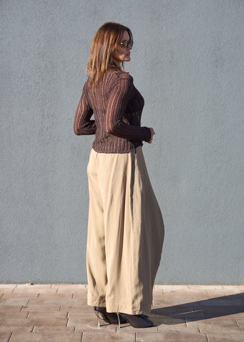 Luźne spodnie w kolorze beżowym, o szerokich nogawkach i miękkiej linii, wykonane z przewiewnego materiału, idealne do stylizacji casual i boho.