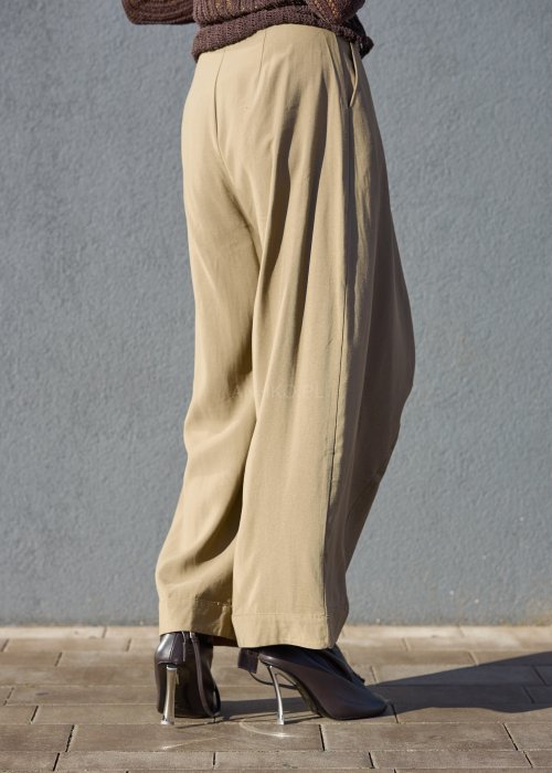 Luźne spodnie w kolorze beżowym, o szerokich nogawkach i miękkiej linii, wykonane z przewiewnego materiału, idealne do stylizacji casual i boho.