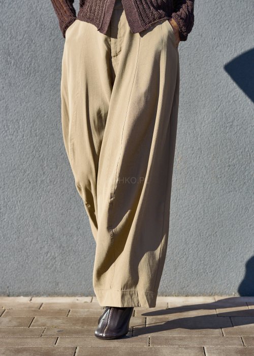 Luźne spodnie w kolorze beżowym, o szerokich nogawkach i miękkiej linii, wykonane z przewiewnego materiału, idealne do stylizacji casual i boho.