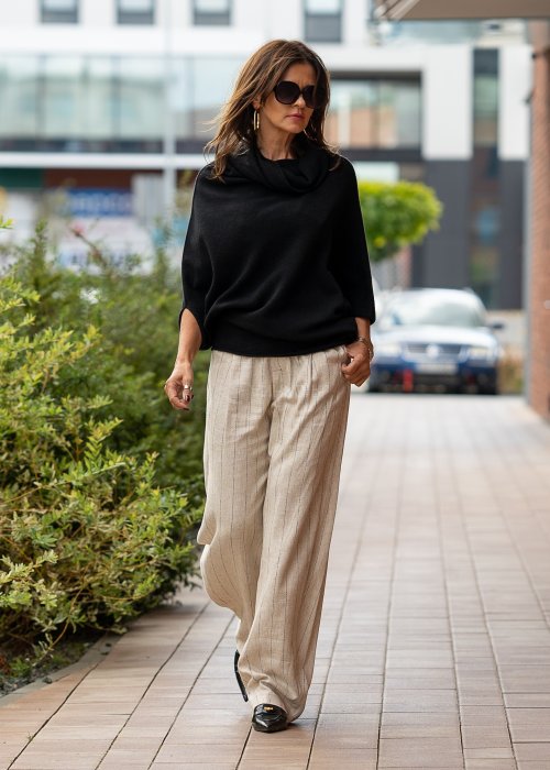 Czarny sweter oversize w stylu poncza z szerokim kołnierzem komin i luźnym krojem. Model w miejskiej stylizacji z eleganckim, minimalistycznym charakterem.