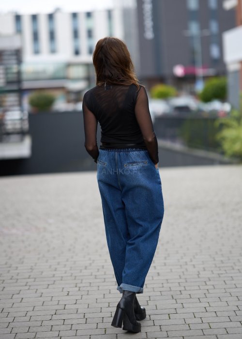 Niebieskie jeansy damskie o kroju slouchy z elastycznym pasem i podwiniętą nogawką. Stylizacja z botkami na obcasie w miejskim, casualowym stylu.