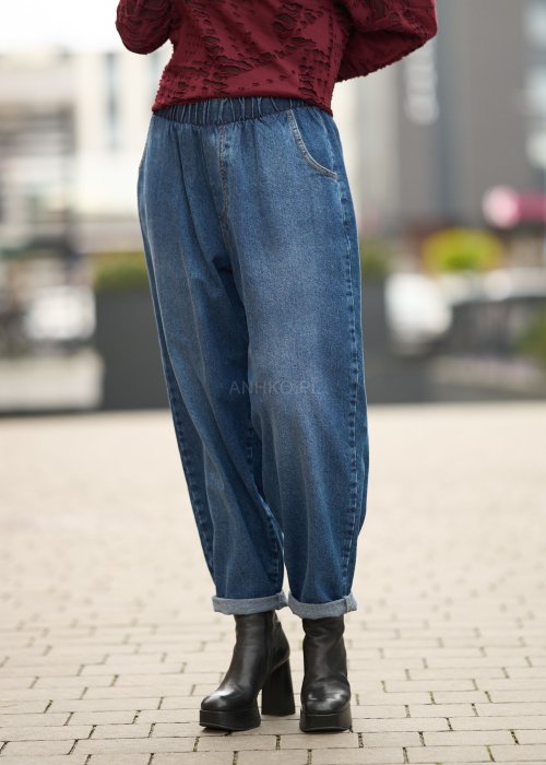 Niebieskie jeansy damskie o kroju slouchy z elastycznym pasem i podwiniętą nogawką. Stylizacja z botkami na obcasie w miejskim, casualowym stylu.