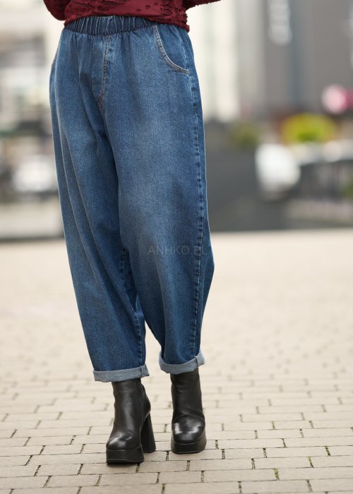Niebieskie jeansy damskie o kroju slouchy z elastycznym pasem i podwiniętą nogawką. Stylizacja z botkami na obcasie w miejskim, casualowym stylu.