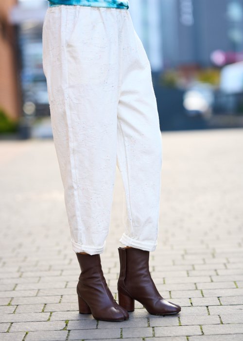 Kremowe spodnie z naturalnej tkaniny, luźna nogawka, elastyczny pas i swobodny fason w stylu boho
