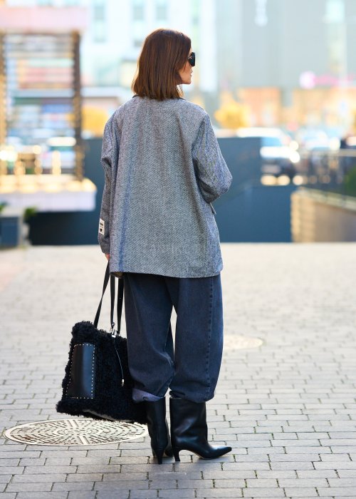 Szara marynarka damska w drobną jodełkę o kroju oversize z ozdobnymi naszywkami, stylizacja z czarnym topem i szerokimi spodniami.