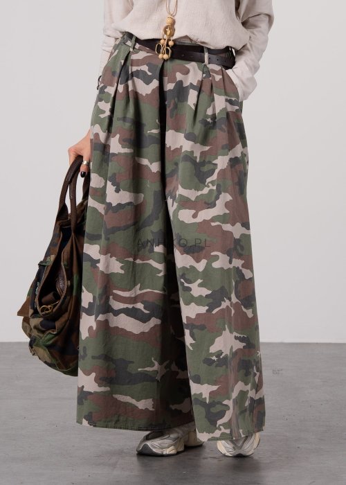 Szerokie spodnie damskie w militarny wzór moro z wysokim stanem i zakładkami w pasie, w stylizacji z paskiem i sneakersami.