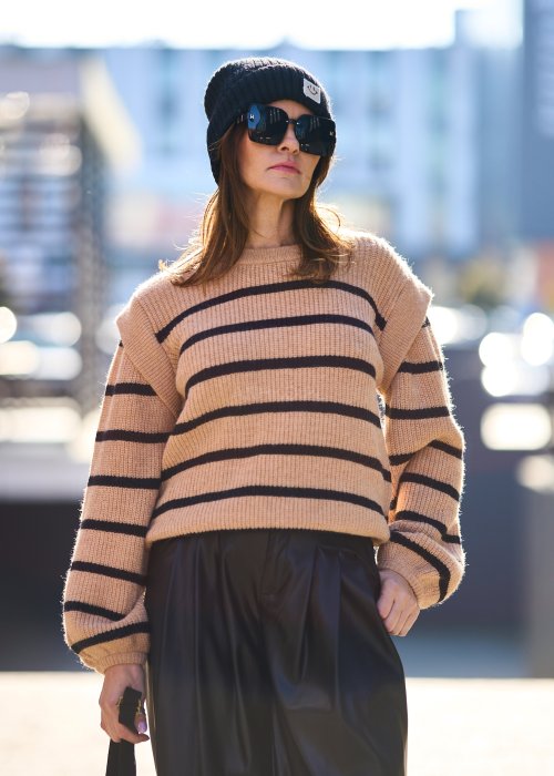 Beżowy sweter oversize w czarne pasy z grubej dzianiny, luźny krój i długie rękawy w modzie damskiej