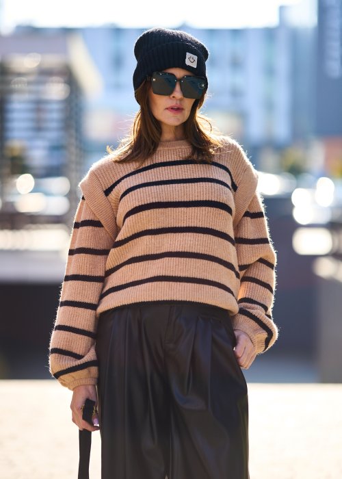 Beżowy sweter oversize w czarne pasy z grubej dzianiny, luźny krój i długie rękawy w modzie damskiej