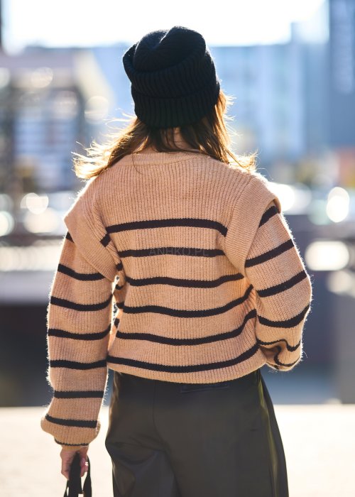 Beżowy sweter oversize w czarne pasy z grubej dzianiny, luźny krój i długie rękawy w modzie damskiej