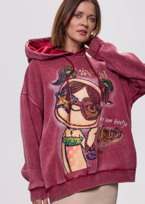 Bordowa bluza z kapturem o luźnym kroju, z dużą artystyczną grafiką postaci i dekoracyjnymi napisami na przodzie; modelka trzyma kaptur, całość sfotografowana na jasnym, neutralnym tle