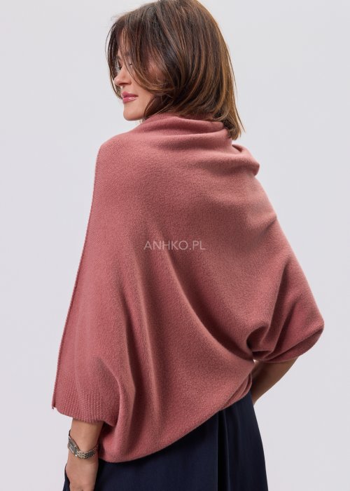 Sweter oversize w kolorze brudnego różu z szerokim kołnierzem typu komin i luźnym krojem poncza. Model prezentowany w stylizacji z ciemnym dołem, podkreślający miękką dzianinę i asymetryczny fason.