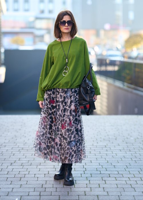 Zielona bluzka oversize z długim rękawem i regulowanym dołem, stylizowana z printowaną spódnicą maxi i botkami w miejskim looku.