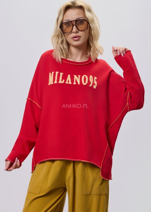 Czerwona bluza damska oversize z haftem „Milano 95” i kontrastowymi przeszyciami, zestawiona z musztardowymi spodniami w stylizacji miejskiej.