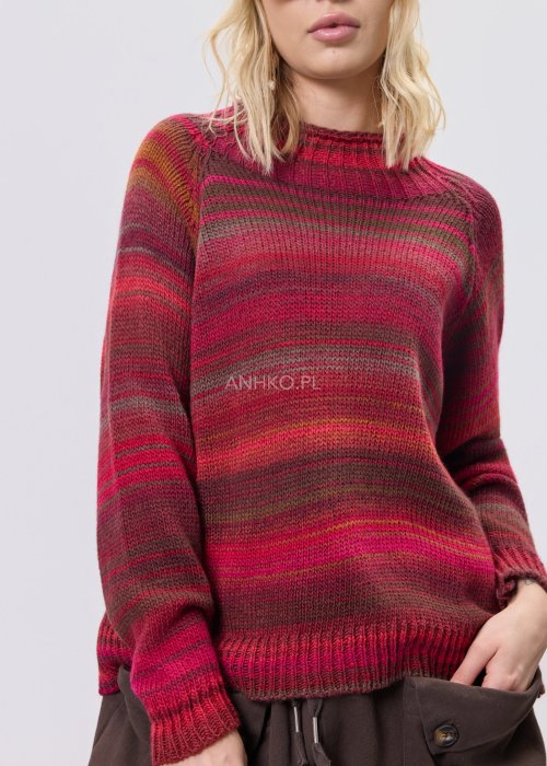 Bordowy sweter damski w wielobarwne paski w odcieniach ziemi, zestawiony z brązowymi spodniami w stylizacji casual na chłodniejsze dni.