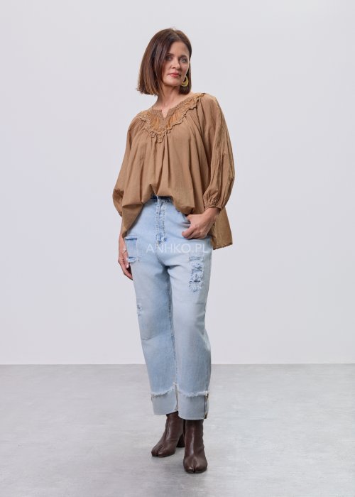Camelowa bluzka damska z haftem przy dekolcie V i luźnym krojem, zestawiona z jasnymi jeansami w stylizacji casual.