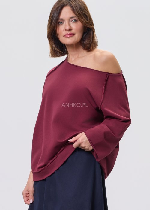 Bordowa bluza damska oversize z raglanowymi rękawami i asymetrycznym dekoltem, stylizowana z granatową spódnicą midi i czarnymi botkami.