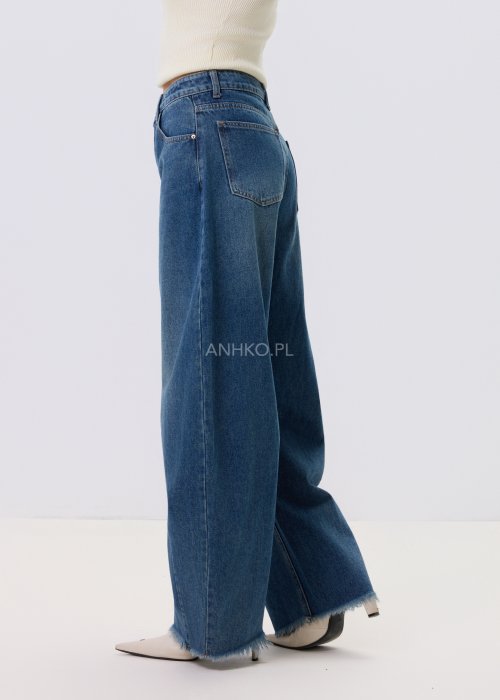 Jeansy damskie Driftline w kolorze ciemnego denimu o szerokiej nogawce i surowym wykończeniu dołu, stylizowane z jasnym topem i botkami na obcasie.