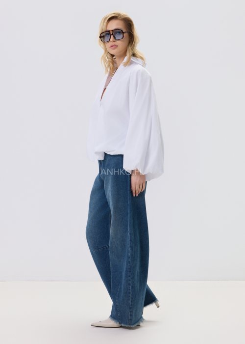 Jeansy damskie Driftline w kolorze ciemnego denimu o szerokiej nogawce i surowym wykończeniu dołu, stylizowane z jasnym topem i botkami na obcasie.