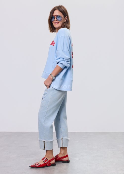 Niebieska bluza oversize Since 1998 z czerwonym nadrukiem z przodu i z tyłu, stylizowana z jasnymi jeansami.