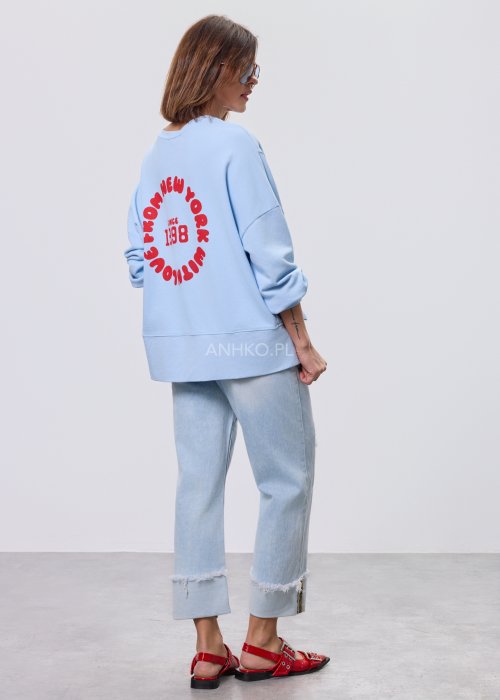 Niebieska bluza oversize Since 1998 z czerwonym nadrukiem z przodu i z tyłu, stylizowana z jasnymi jeansami.